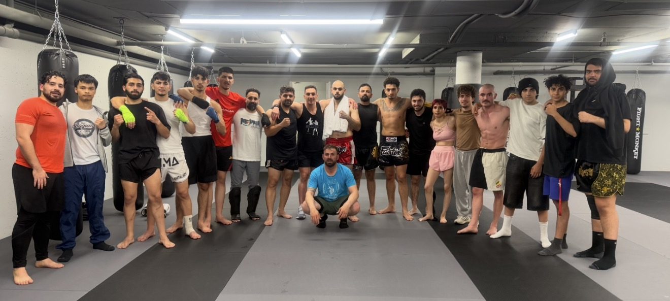 DKM Academy team standing together on the gym floor between the heavy bags