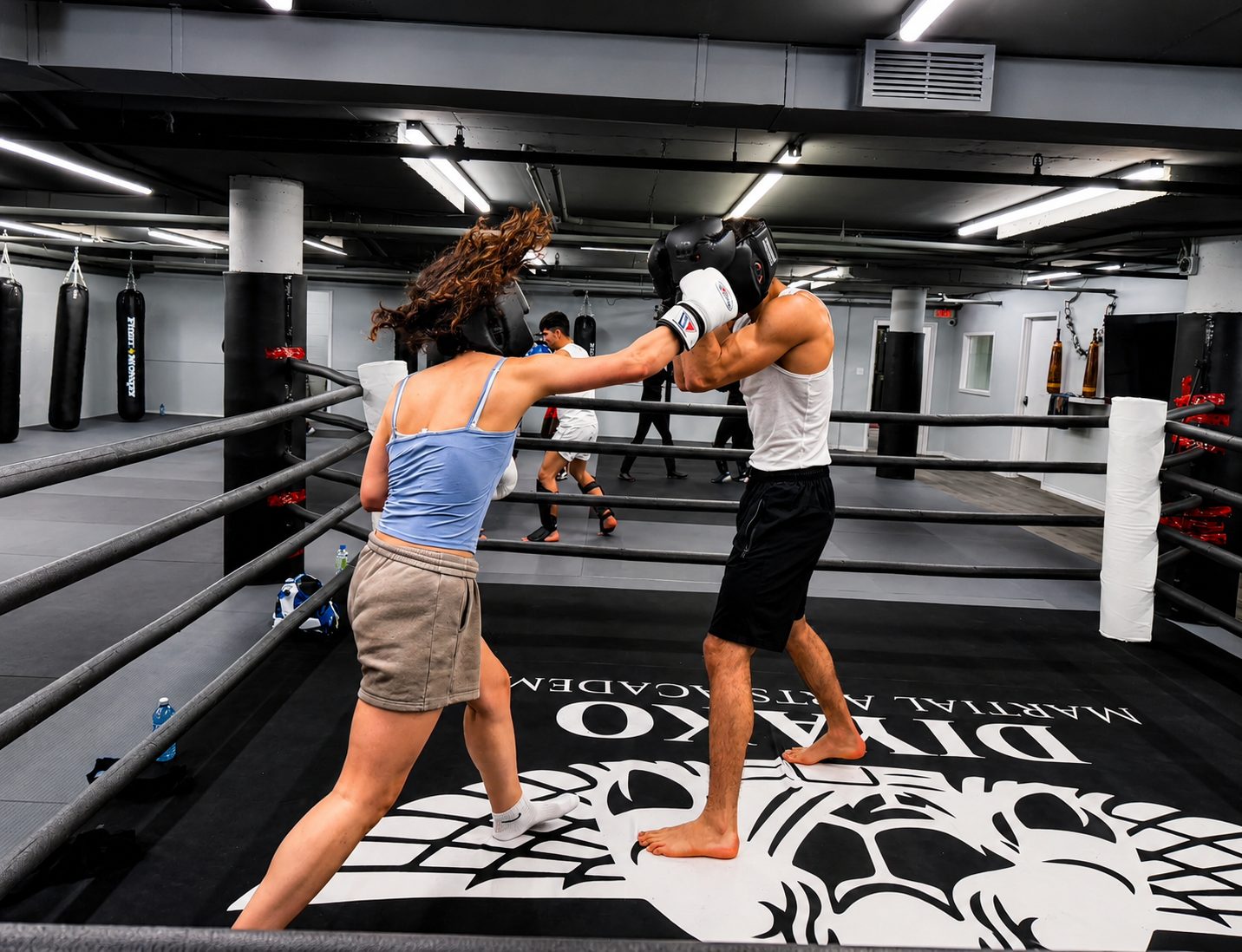 Two athletes sparring with headgear in the DKM ring over the crest logo