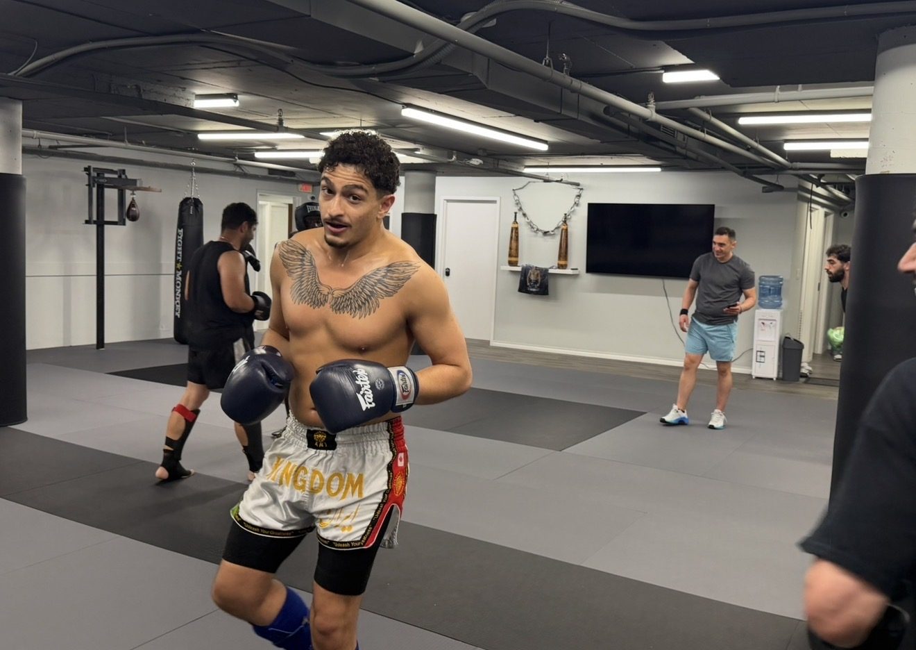 Fighter in Kingdom Muay Thai shorts with gloves up between rounds