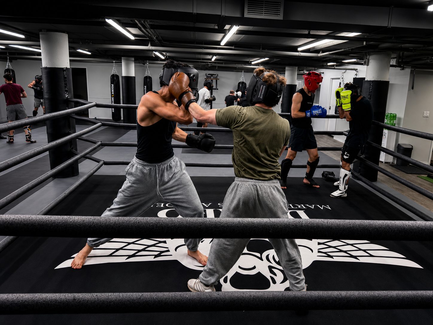 Fighters sparring inside the DKM Academy boxing ring with the winged crest on the canvas